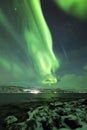 Northern lights, aurora borealis, above a fjord surrounded by a Royalty Free Stock Photo