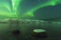 Northern lights Aurora borealis at the lakeside with rocks of a