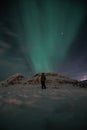 Northern lights, aurora borealis over Iceland mountains in Iceland and with person who is looking up on sky during winter. Royalty Free Stock Photo