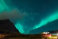 Northern lights Aurora Borealis over illuminated fishing village of reine lofoten islands. Royalty Free Stock Photo