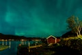 Northern lights Aurora Borealis over illuminated fishing village of reine lofoten islands. Royalty Free Stock Photo