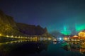 Northern lights Aurora Borealis over illuminated fishing village of reine lofoten islands. Royalty Free Stock Photo