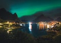 Northern lights Aurora Boreals over illuminated fishing village of reine lofoten islands. Royalty Free Stock Photo