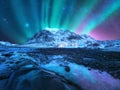 Northern lights over the mountain, sea coast, city lights Royalty Free Stock Photo