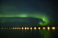 Northern polar light Aurora borealis glowing under the starry dark sky and water reflection from lake