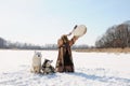 Northern shaman beats tambourine performing a rite calls spring. Husky dogs. Winter landscape