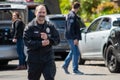 A white male detective from LAPD`s metro division walks by police vehicles