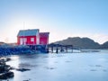 Norway fishing village on stony island. Shinning red white houses in quiet bay. Smooth water level mirroring Royalty Free Stock Photo