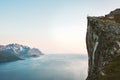 Norway landscape man raised hands on cliff rock edge above fjord Senja mountains scenery travel hiking Royalty Free Stock Photo