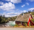 Norway with typical red cottage against wild river. Railroad from Flam to Myrdal