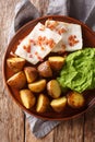 Norwegian cod lutefisk served with pea puree, potatoes and bacon close-up. vertical top view Royalty Free Stock Photo