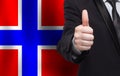 Norwegian concept. Businessman showing thumb up on the background of flag of Norway