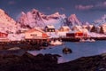 Norwegian fishing village with red rorbu houses, mountain peaks and sea coast winter sunset landscape, Lofoten islands, Norway Royalty Free Stock Photo