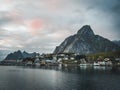 Norwegian fishing village Reine at the Lofoten Islands in Norway. Dramatic sunset clouds moving over steep mountain