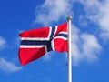 The Norwegian flag against a blue sky with clouds Royalty Free Stock Photo