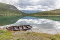 Norwegian landscape with a boat on lake against mountains. Fishing boat on a still lake in Norway and high mountains in background Royalty Free Stock Photo