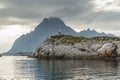 Norwegian seascape, lighthouse on the island, rocky coast with dramatic skies, the sun breaks through the clouds, sheer