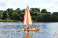 Young woman or girl sailing on sailboat on sunny day on river or lake with trees background Royalty Free Stock Photo