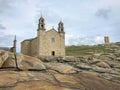 Nosa Senora of Barca Church on the ancient sacral stones of rocky cape. Beach in Muxia, Galicia, Spain