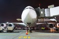 Nose and cockpit airplane gangway of the terminal building at the airport at night, aircraft flight maintenance. Royalty Free Stock Photo