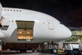 Nose and cockpit airplane with open luggage compartment at passenger gangway of the terminal building at the airport at night, air Royalty Free Stock Photo