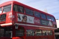 A nostalgic graphic Coca-Cola advertising poster on a traditional red London Double Decker Bus