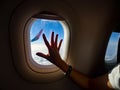 Nostalgic woman passenger hand touching plane window with view of wing