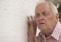 Nosy neighbour holding a glass up to the wall