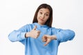 Not bad. Young woman smirk, shows like dislike, thumbs up and thumbs down gesture, medium rating, average result Royalty Free Stock Photo