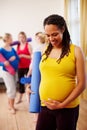 Not much longer to go now...A happy young pregnant African-American woman holding her exercise mat and looking down at Royalty Free Stock Photo