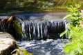 The clear water of a small stream drops over low rocks making a small waterfall Royalty Free Stock Photo