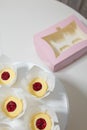 Not ready cupcakes. Pastry with jam layer without cream in white paper cover on table, top view. Pink box. Homemade desserts,