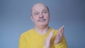 Senior man clapping and applauding with disbelief at his face. Studio shot