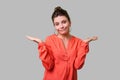 Not sure! Portrait of uncertain confused woman with bun hairstyle, big earrings and in red blouse. indoor studio shot isolated on Royalty Free Stock Photo