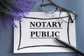 NOTARY PUBLIC - word on a white sheet against the background of glasses, pens and lavender