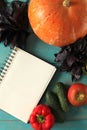 Note book and composition of vegetables on blue wooden desk. Royalty Free Stock Photo