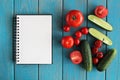 Note book and composition of vegetables on blue wooden desk. Royalty Free Stock Photo