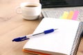 A note book, laptop, pen, graph paper document on the office desk table behind white blind