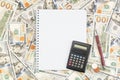 Note book with pen, coins and calculator on the background of dollar bills Royalty Free Stock Photo