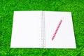 Note book with red pen placed or put on green grass Royalty Free Stock Photo