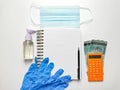 Note book with rubber hand glove,sanitizer bottle,mask,calculator and money on white desk. Royalty Free Stock Photo