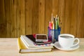 Note book,smart phone,coffee cup,and stack of book on wooden tab Royalty Free Stock Photo