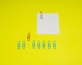 Note with color paper clip isolated on yellow background Royalty Free Stock Photo