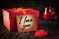 Note with the inscription I love you on a red gift box on a wooden background: concept of a romantic gift and declaration of love Royalty Free Stock Photo