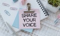 Note with the message of share your voice, with desk background Royalty Free Stock Photo