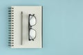 Note pad with eyeglasses and pencil composition on blue background Royalty Free Stock Photo