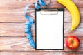 Note paper, measuring tape, banana and apple on a wooden background. Diet, meal plan. Healthy food concept. Flatlay. Top view. Royalty Free Stock Photo