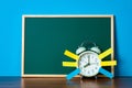Note paper sticky and vintage alarm clock and blank green chalkboard on table with copy space for add text notice something, list Royalty Free Stock Photo