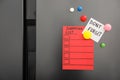 Note with phrase DON`T FORGET, shopping list and magnets on refrigerator
