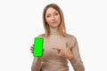 Note that. Pretty young blond woman is pointing finger at mobile phone blank screen in her hand Royalty Free Stock Photo